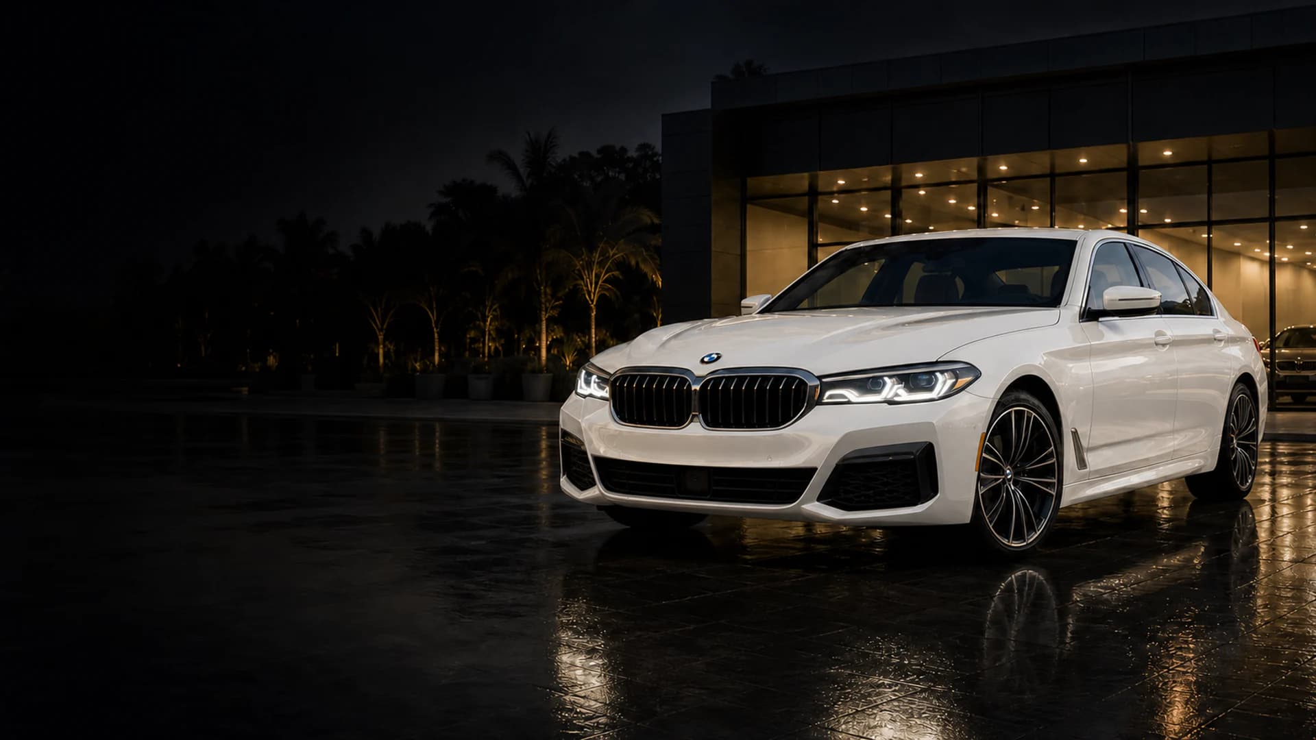 Pearl white BMW 5 Series outside a premium showroom at night