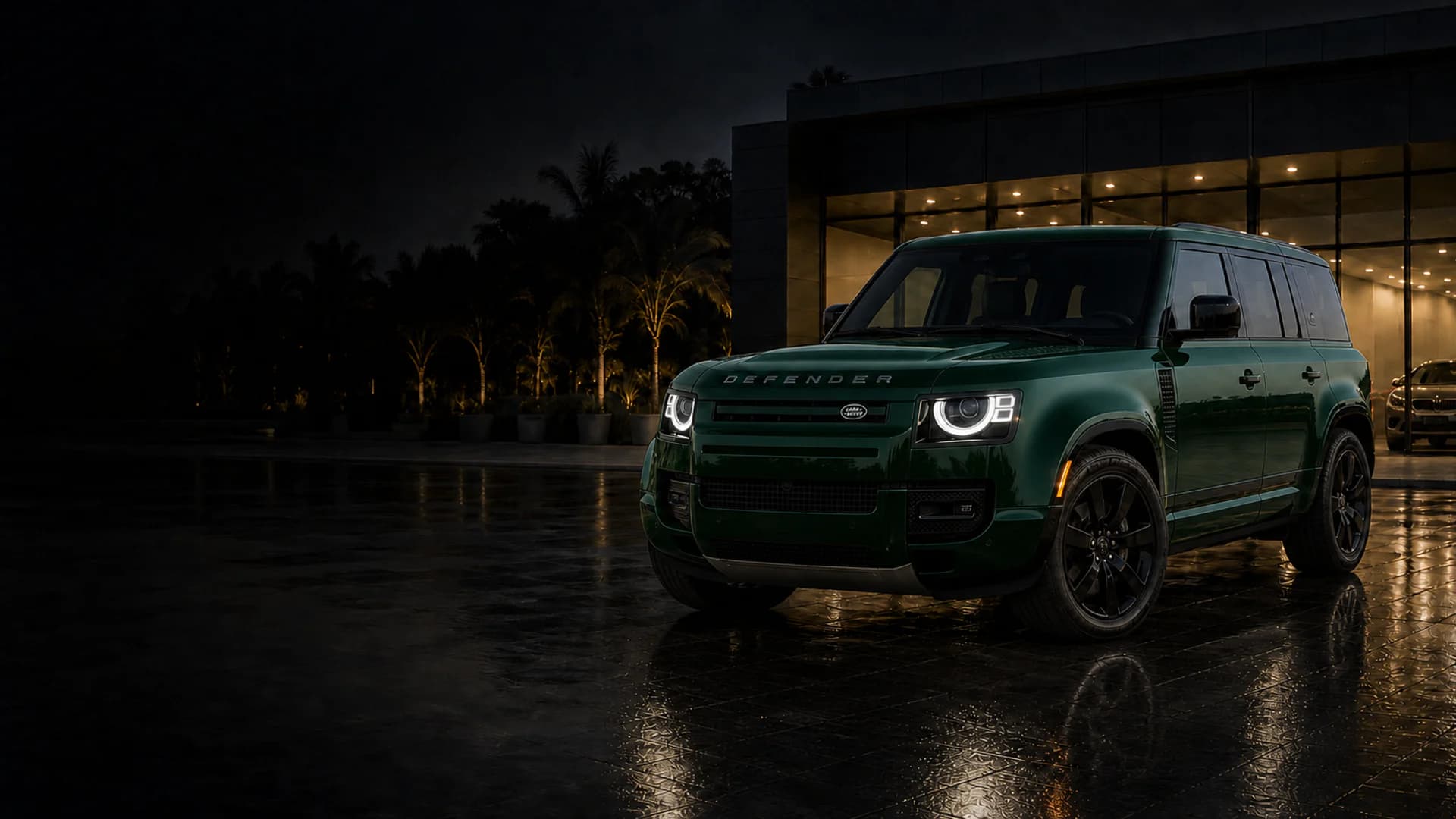 British racing green Land Rover Defender 110 outside a premium showroom at night